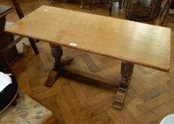 A reproduction oak rectangular top coffee table on carved cup and cover supports united by central