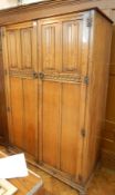 A reproduction mahogany double wardrobe, the panelled doors with linenfold carving,