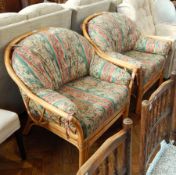 A pair of conservatory cane armchairs with loose cushion back and seats