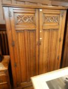 An oak carved linenfold and floral guilloche double wardrobe together with a matching mirror back