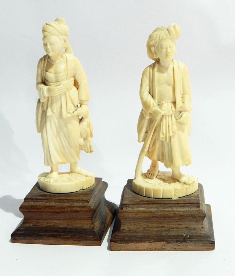 Pair of Japanese ivory figures of a man carrying a gun and a woman carrying a duck,