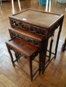 A nest of three Chinese hardwood occasional tables with pierced fretwork frieze on turned legs