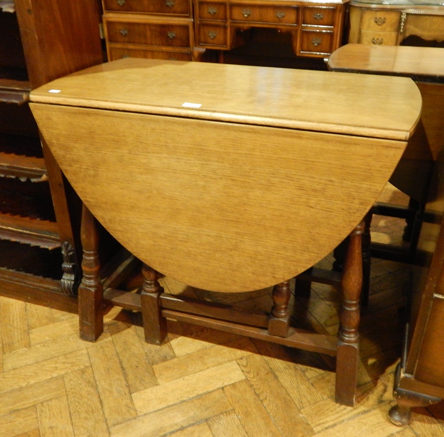 A modern oak oval top gateleg table, on baluster turned legs united by stretchers,