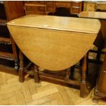 A modern oak oval top gateleg table, on baluster turned legs united by stretchers,