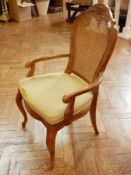 A pair of oak elbow chairs with cane backs, upholstered green cushions,