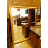 A large rectangular wall mirror within a carved gilded frame,