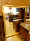 A large rectangular wall mirror within a carved gilded frame,