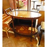 A mahogany oval top two tier tea trolley on turned supports with castors,