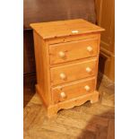 Pine bedside cabinet with three long drawers, turned and bun handles, on shaped feet,
