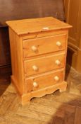 Pine bedside cabinet with three long drawers, turned and bun handles, on shaped feet,