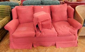 A red upholstered three seater sofa with matching footstool