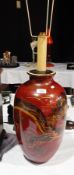 A large oriental style jar painted with a dragon, on dark red ground,