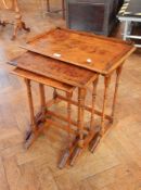 A nest of three burrwood occasional tables, on ring turned column supports,