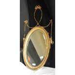 A mirror with carved wooden frame with beaded edges and ribbon and swag decoration