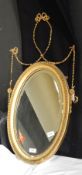 A mirror with carved wooden frame with beaded edges and ribbon and swag decoration