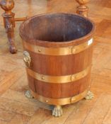 A brass bound log bucket with brass liner, lion mask ring handles on paw feet,