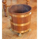 A brass bound log bucket with brass liner, lion mask ring handles on paw feet,