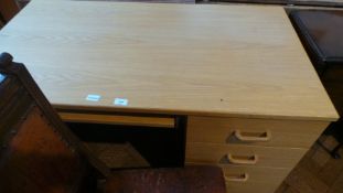 A pale wood desk with sliding shelf and three short drawers,