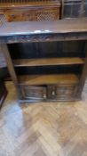 An oak open bookcase with foliate carved frieze,