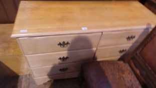 A modern light wood chest of six drawers raised on bracket feet with brass handles,