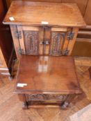 An oak reproduction side cupboard with pair of foliate carved doors enclosing shelf, on turned legs,