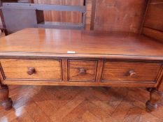 A stained oak coffee table with three short drawers,