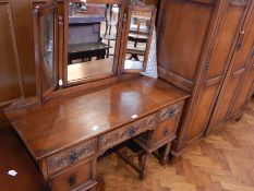 A reproduction oak double wardrobe with carved panel doors enclosing hanging space and shelves