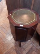 A modern mahogany octagonal top cupboard with inset writing surface raised on splayed legs,