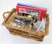 A wicker basket containing various sewing and embroidery silks, needles, scissors, etc.