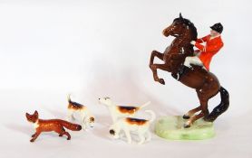 A Beswick huntsman on a rearing horse with three hounds,
