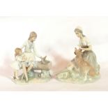 A Nao figure of a girl petting a large dog and a Nao group of a girl with a little girl,