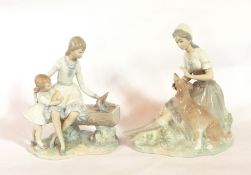 A Nao figure of a girl petting a large dog and a Nao group of a girl with a little girl,