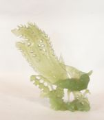 20th century carved jade model of a pheasant/peacock standing on rocky outcrop among foliage,