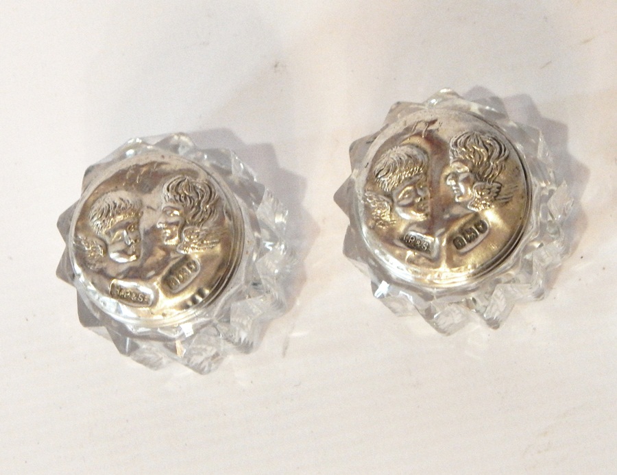 A pair of silver-capped glass toilet jars with cherub pattern,