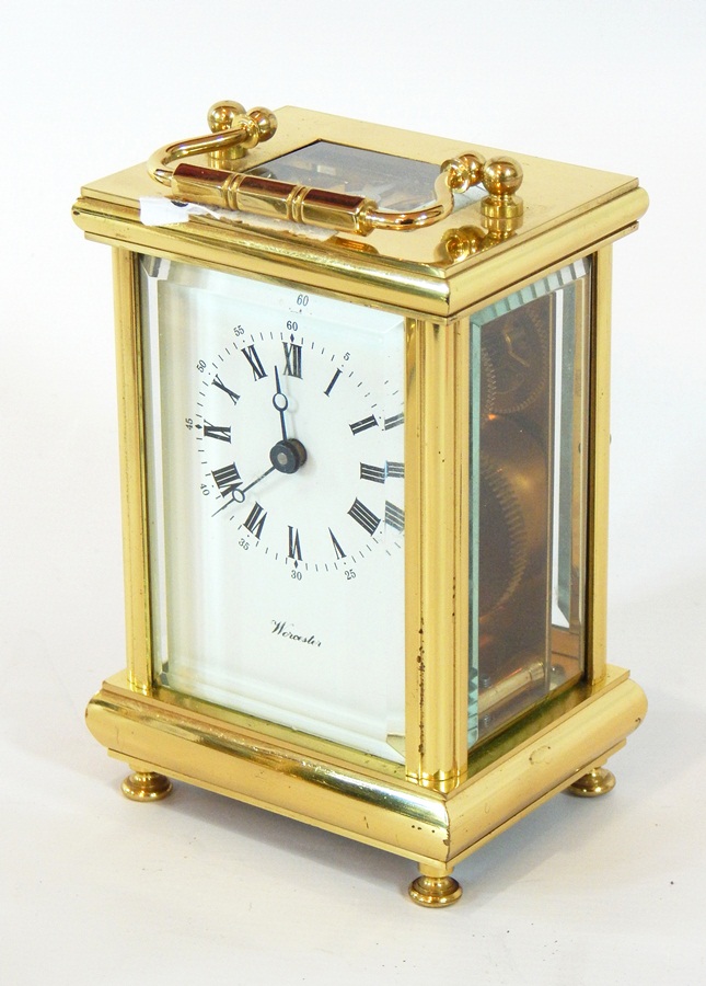 A brass carriage clock timepiece with glazed panels, enamel dial with Roman numerals,