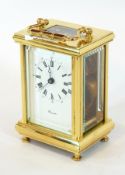 A brass carriage clock timepiece with glazed panels, enamel dial with Roman numerals,