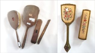 A silver-backed dressing table set comprising hand mirror, hairbrush and comb mount,