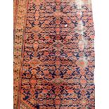 A Persian style rug with blue ground, geometric pattern, cream guard fences and red border,