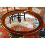 A carved oak oval frame wall mirror with bevelled plate,