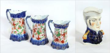 A pottery character jug of an admiral and three graduated jugs with blue base and top with red and