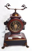 A Victorian red and black marble mantel clock, with ring handles and paw feet,