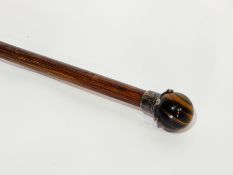 A silver-mounted tiger's eye swagger stick together with a white metal topped malacca cane (2)