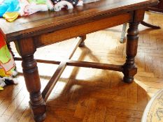 An oak extending dining table on cup and ball block supports with bun feet,