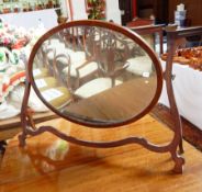 A large mahogany oval shaped wood mirror on shaped supports