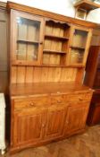A modern pine dresser, the plate rack with a pair of glazed cupboards and open shelves,