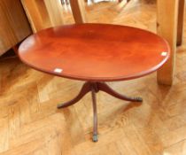 A contemporary oval top coffee table on pillar support with quadruped splayed legs,