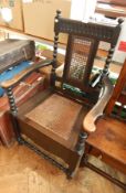 A late 19th century stained oak commode chair, with cane panel back and seat,