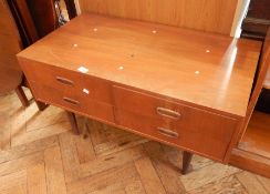 A small teak side table with four short drawers, on cylindrical tapering legs,