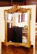 A gilt overmantel mirror with a floral pediment of birds, beaded border,