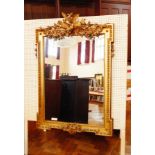 A gilt overmantel mirror with a floral pediment of birds, beaded border,